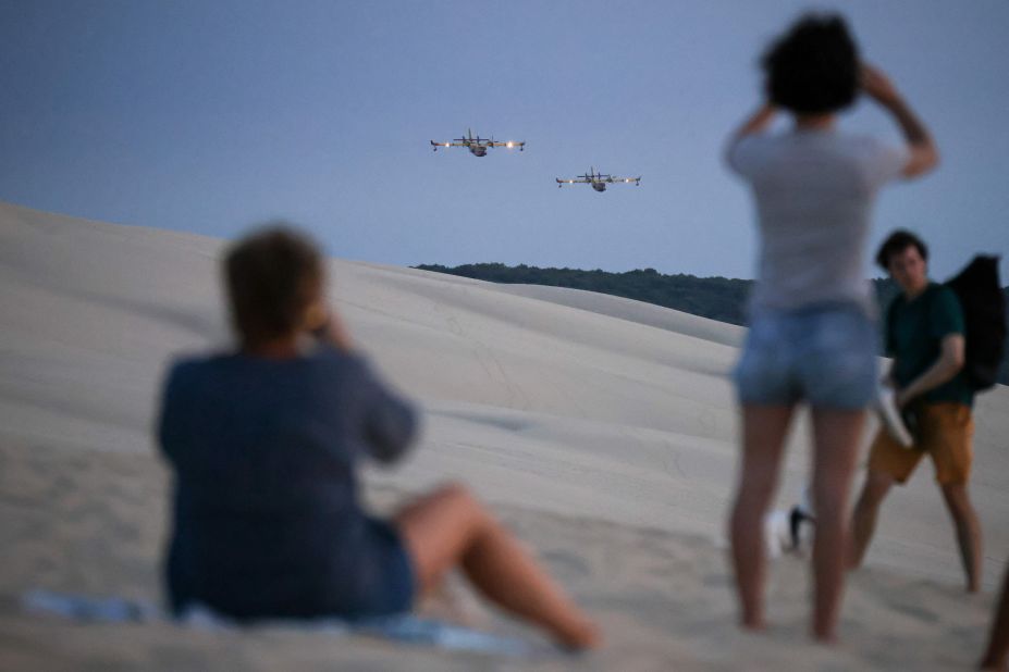 People take pictures of firefighting aircraft flying over La Teste-de-Buch, France, on July 14.