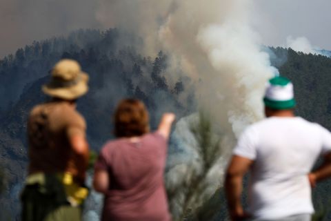 Residents watch as a column of smoke emerges from a fire in A Pobra do Brollón, Spain, on July 17.