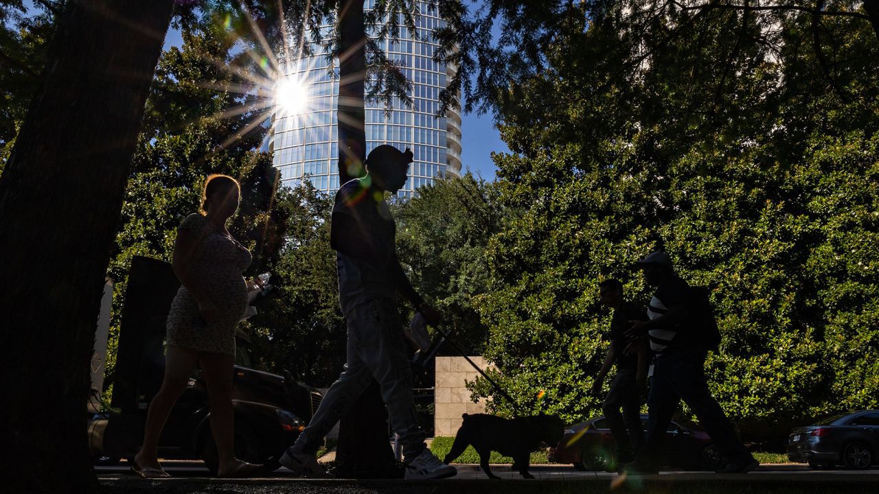 Pedestrians walk along a street during a heatwave in Dallas, Texas.