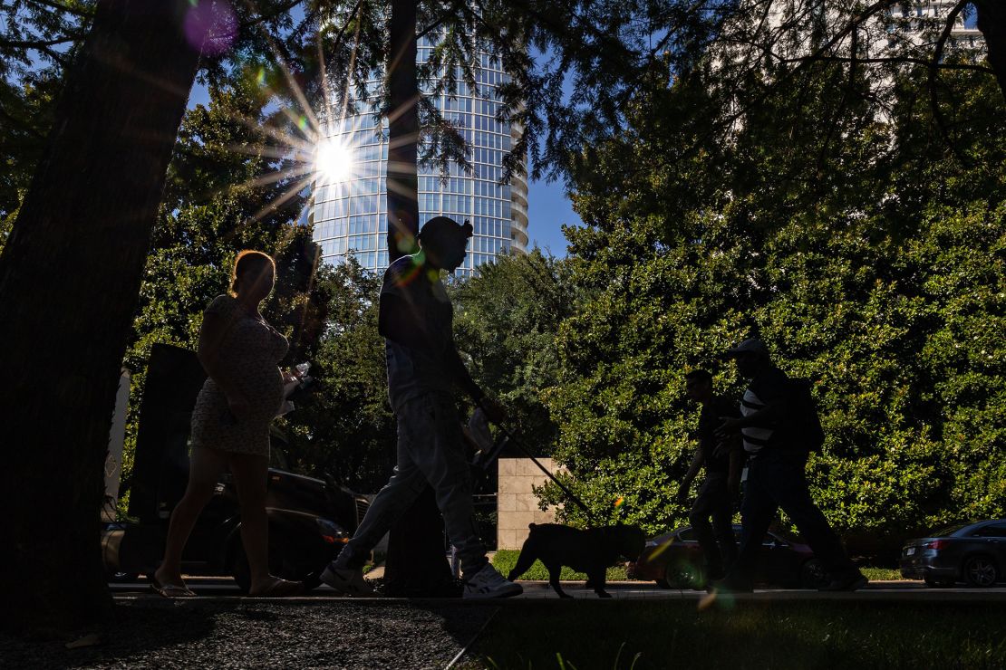 Pedestrians walk along a street during a heatwave in Dallas, Texas.