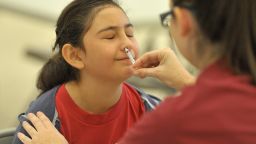 A student gets the FluMist vaccine, which stimulates mucosal immunity.