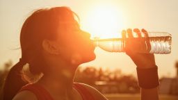 Female drinking a bottle of water  , sunset