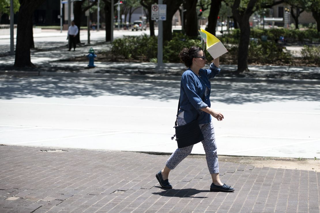 A pedestrian walks with a bag covering her face to block the sun during a heatwave in Houston, Texas.