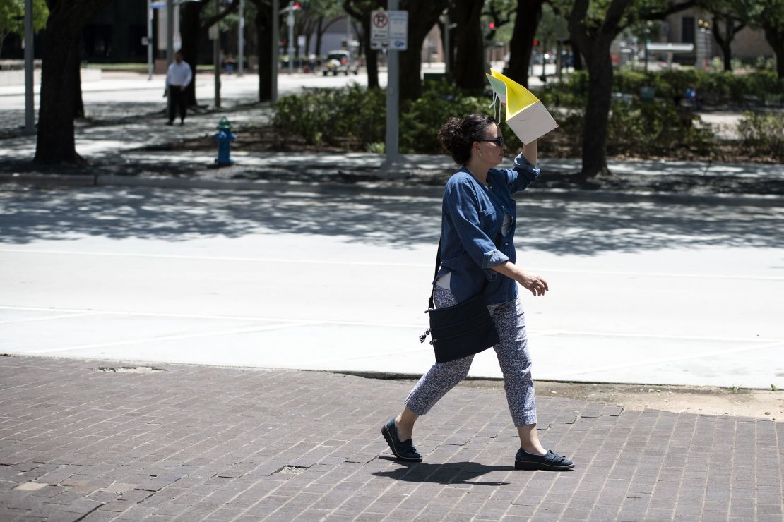 A pedestrian walks with a bag covering her face to block the sun during a heatwave in Houston, Texas. 