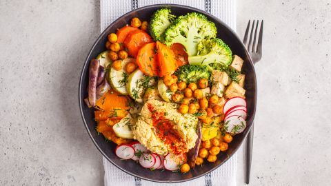 A healthy plant-based meal features a colorful mix of vegetables, chickpeas, hummus and tofu. 