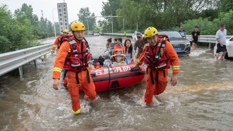 2021 年 7 月 23 日，救援人员在中国中部河南省郑州的一条高速公路入口处帮助疏散滞留居民。 