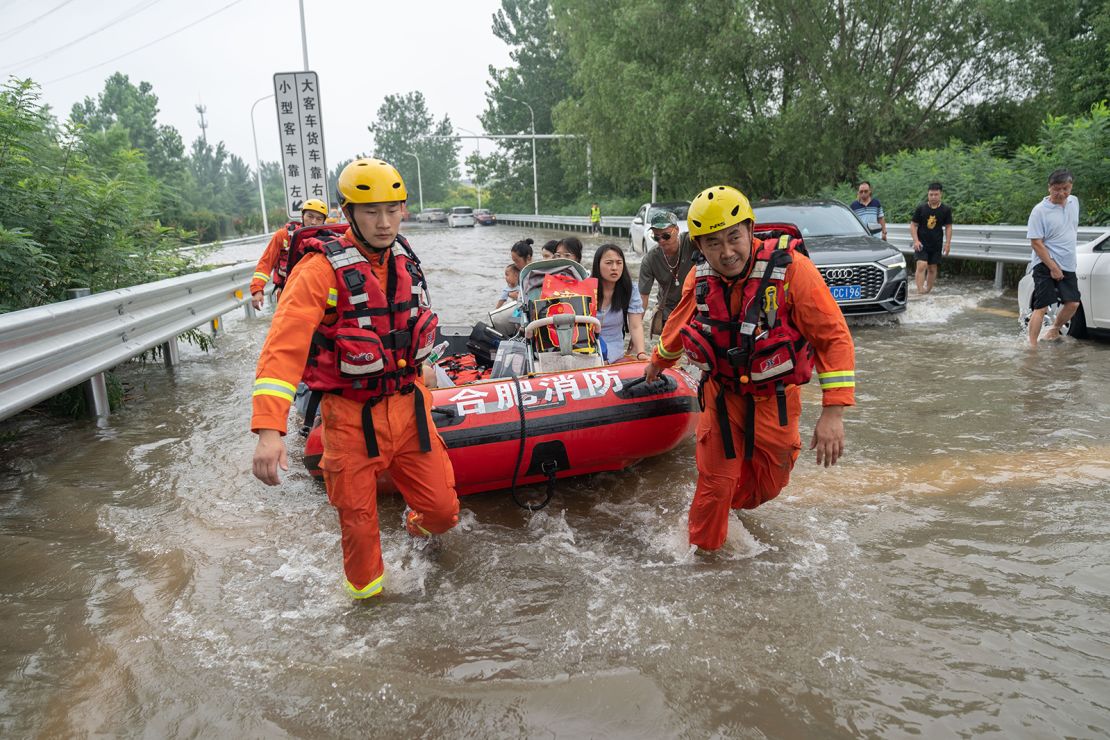 Rescuers help evacuate stranded residents at the entry to an expressway in flood-hit Zhengzhou, central China's Henan Province on July 23, 2021. 