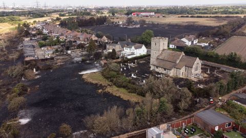 A scorched cemetery surrounds a church after a massive fire broke out in Vennington, east London, on Tuesday.  Britain experienced a record-breaking heatwave this week.  