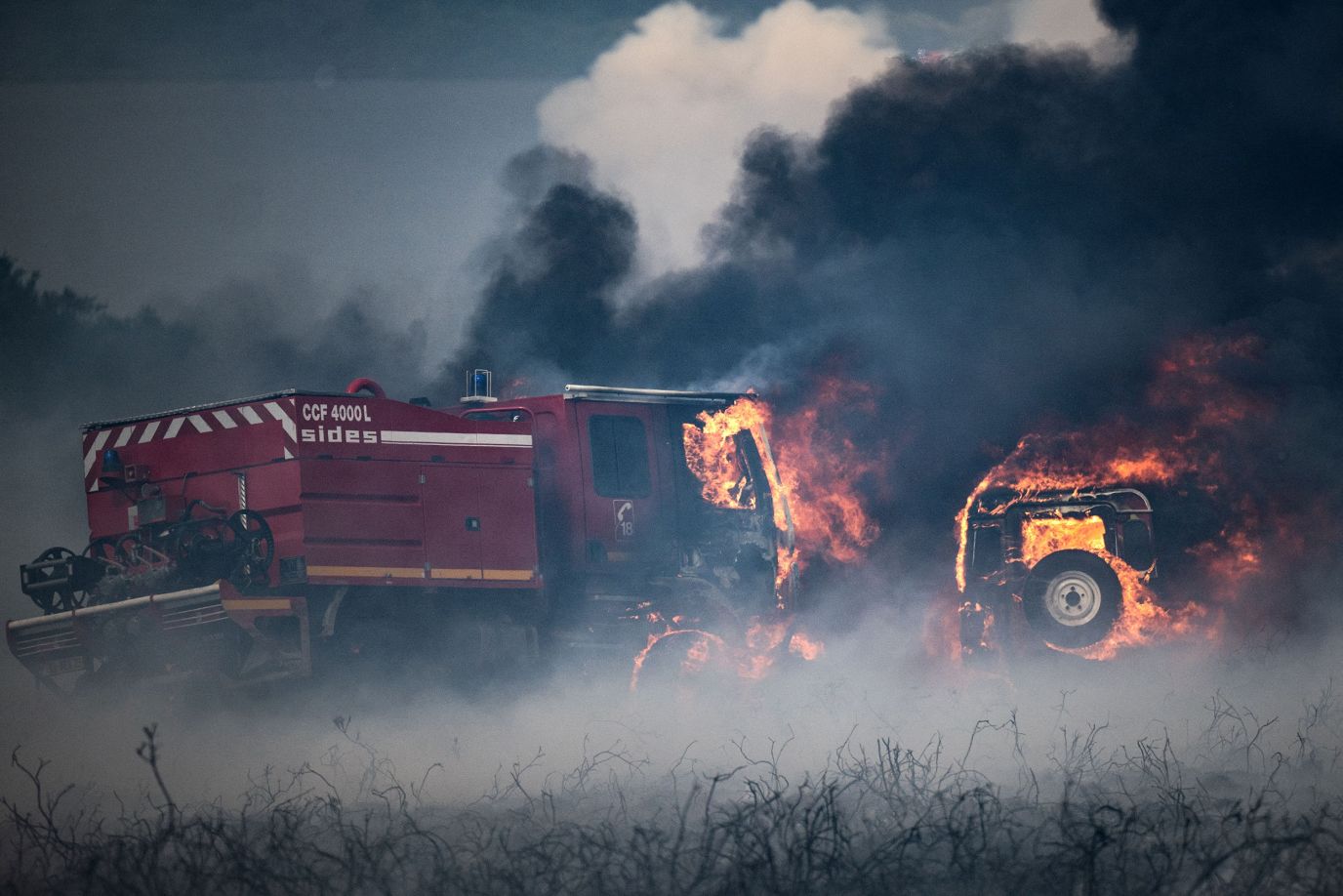 Firefighting vehicles are ablaze during a wildfire