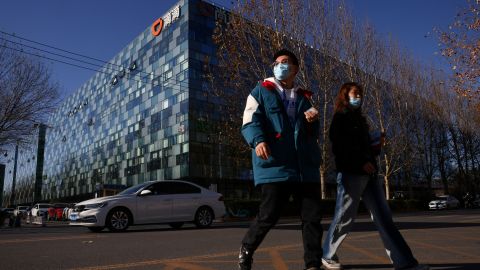 People walk past the headquarters of the Chinese ride-hailing service Didi in Beijing, China, December 3, 2021.