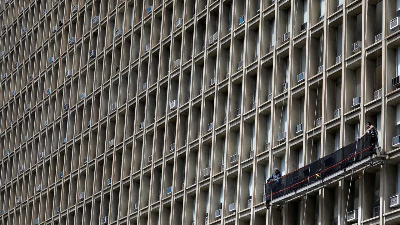 Window washers work on a building featuring rows of air conditioners in New York City, in April last year.