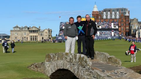 (L-R) English golfers Tony Jacklin and Nick Faldo pose with Cannon at Swilcan Bridge ahead of the 144th Open Championship in St Andrews, Scotland in 2015.
