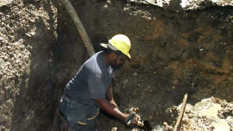 Un trabajador de la construcción cava un hoyo alrededor de una línea de flotación rota de 20 pulgadas en Fort Worth, Texas, mientras comienzan las reparaciones en una línea defectuosa bajo la presión de temperaturas récord.