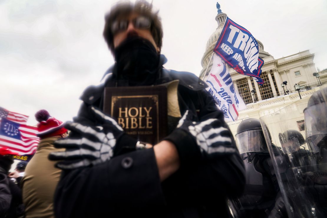 A Trump supporter holds a Bible as he gathers with others outside the Capitol, Jan. 6, 2021, in Washington. (AP Photo/John Minchillo)