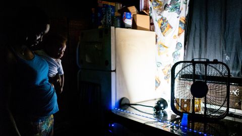 A family in Houston, Texas stands close to a large fan, attempting to find any relief from the relentless heat.