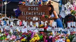 TOPSHOT - A girl lays flowers at a makeshift memorial at Robb Elementary School in Uvalde, Texas, on May 28, 2022. (Photo by CHANDAN KHANNA / AFP) (Photo by CHANDAN KHANNA/AFP via Getty Images)