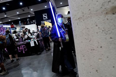 Un asistente vestido como Jedi lleva un sable de luz en el piso de la convención el 21 de julio.