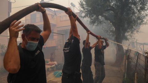 Police officers and locals attempt to extinguish a wildfire burning in the village of Vatera, Greece, on July 23.