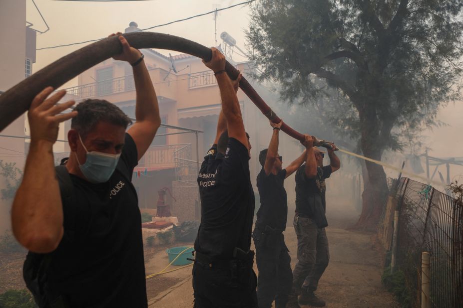 Police officers and locals attempt to extinguish a wildfire burning in the village of Vatera, Greece, on July 23.