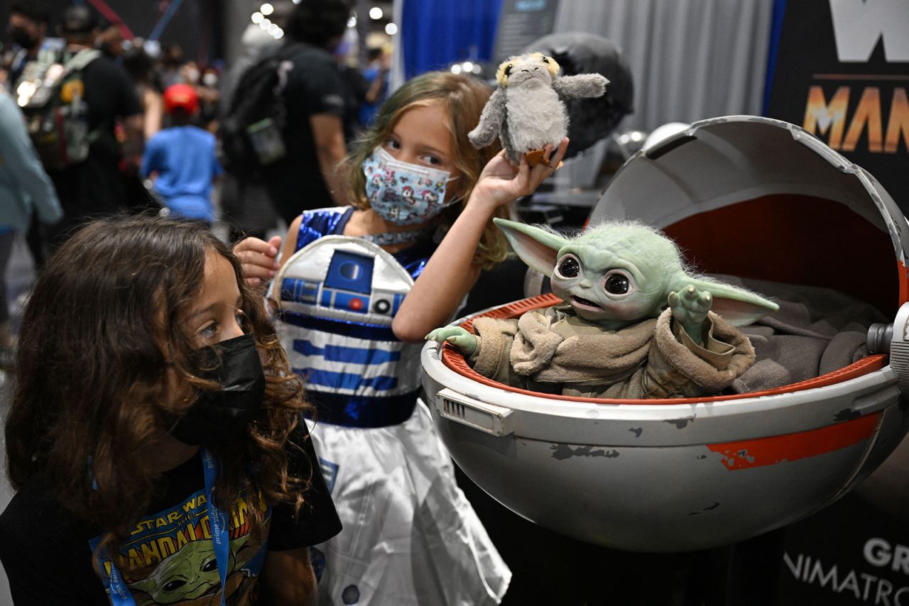 Children look at the animatronic Grogu Baby Yoda puppet from Star Wars "The Mandalorian" at Comic-Con International in San Diego, California, on July 23, 2022.  The starting price for the lifelike moving and emoting collectible is more than $100,000.