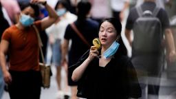 A woman wearing face mask uses a fan as she walks on a street on a hot day, following the coronavirus disease (COVID-19) outbreak in Shanghai, China July 19, 2022. 