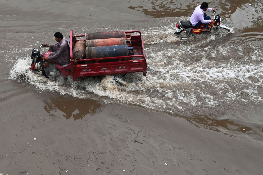 People drive across a flooded street after heavy rainfall in Lahore, Pakistan on July 21, 2022. 