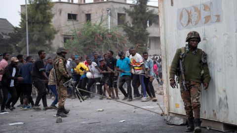 Congolese policemen supervise as protesters pull a container used to barricade the road near the compound of a United Nations peacekeeping force's warehouse in Goma in the North Kivu province of the Democratic Republic of Congo July 26, 2022.