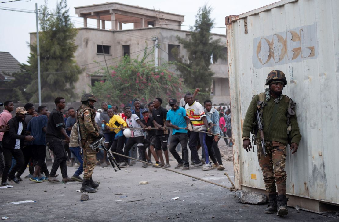 Congolese policemen supervise as protesters pull a container used to barricade the road near the compound of a United Nations peacekeeping force's warehouse in Goma in the North Kivu province of the Democratic Republic of Congo July 26, 2022.