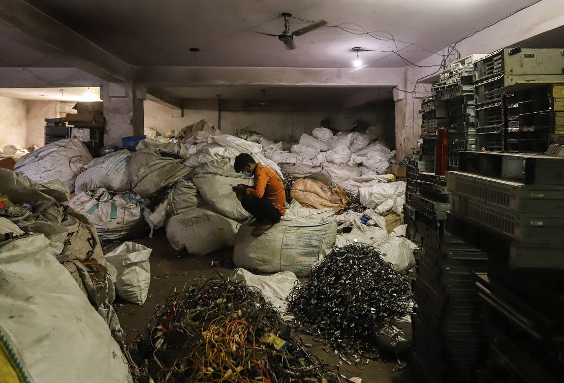 A man sits in front of electronic waste or e-waste from computers at a workshop in New Delhi, India, in July 2020.