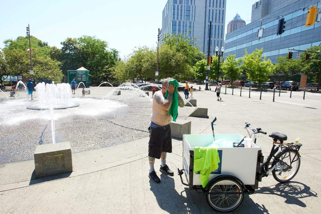 Matthew Carr dries himself after cooling off in the Salmon Street Springs fountain before returning work cleaning up trash on his bicycle in Portland, Oregon, on Tuesday. 