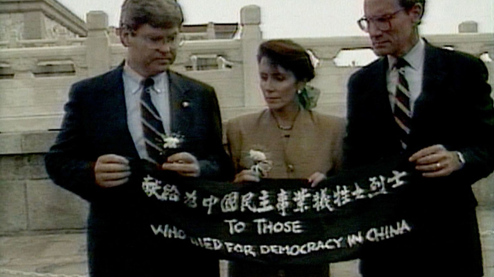 In this image taken from video, Pelosi and fellow US Reps. Ben Jones, left, and John Miller unfold a banner during a trip to Beijing in September 1991. The banner says, "To those who died for democracy in China."