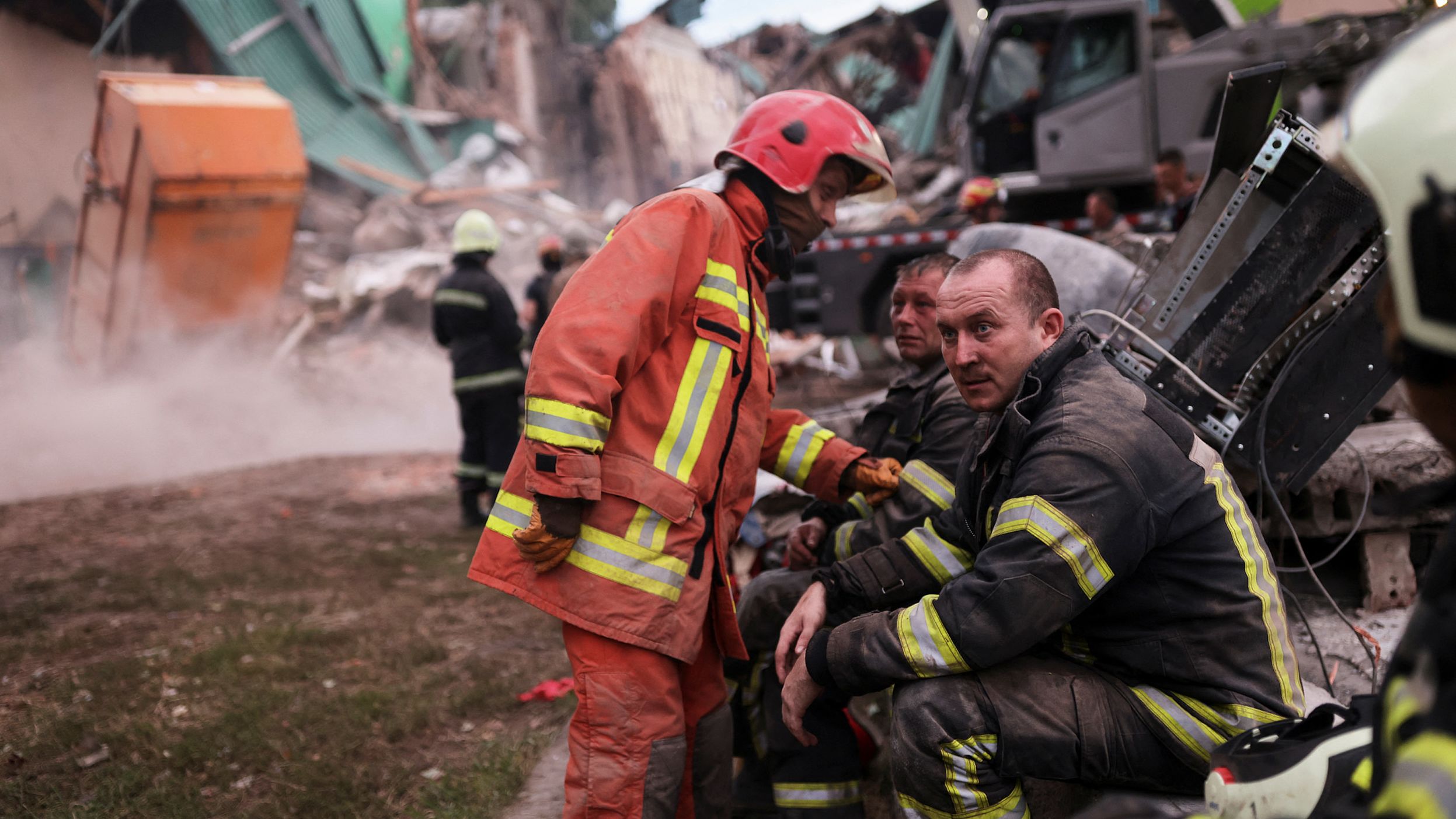 Firefighters rest as their colleagues remove debris during the search for bodies at the Central House of Culture, in Chuhuiv, Ukraine, after an air strike on July 25.