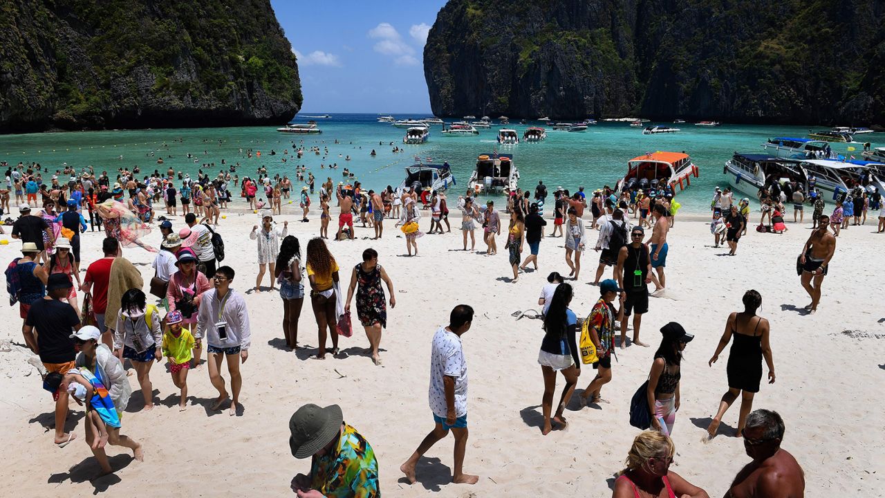 This photo taken on April 9, 2018 shows a crowd of tourists on the Maya Bay beach, on the southern Thai island of Koh Phi Phi.  
Across the region, Southeast Asia's once-pristine beaches are reeling from decades of unchecked tourism as governments scramble to confront trash-filled waters and environmental degradation without puncturing a key economic driver. / AFP PHOTO / Lillian SUWANRUMPHA / TO GO WITH AFP STORY "THAILAND-INDONESIA-PHILIPPINES-TOURISM-ENVIRONMENT" by Lillian SUWANRUMPHA with Joe FREEMAN        (Photo credit should read LILLIAN SUWANRUMPHA/AFP via Getty Images)