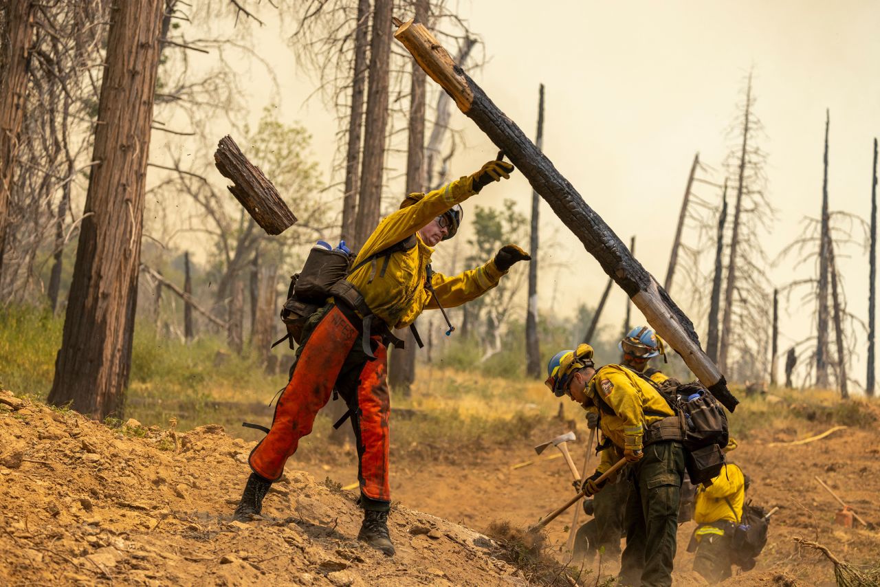 Firefighters cut vegetation near Mariposa to widen the fire line carved by a bulldozer on Monday.