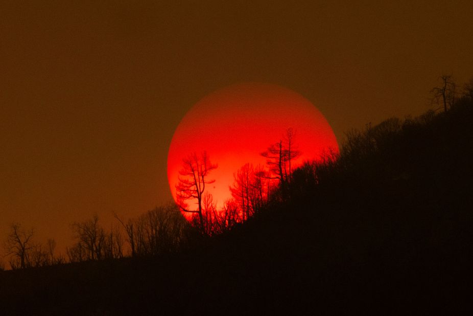The sun sinks behind a smoky sky and burned forest near Mariposa on Sunday, July 24.