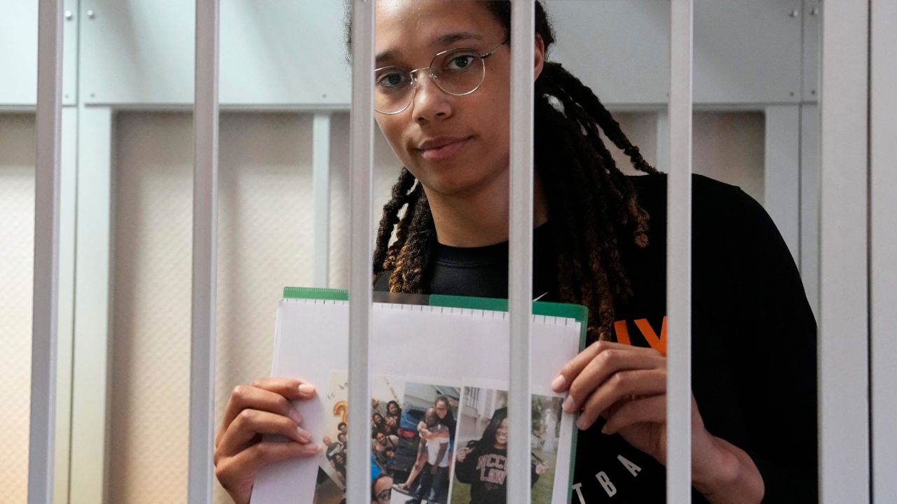 Brittney Griner holds photographs standing inside a defendants' cage before a hearing at a court outside Moscow Wednesday.