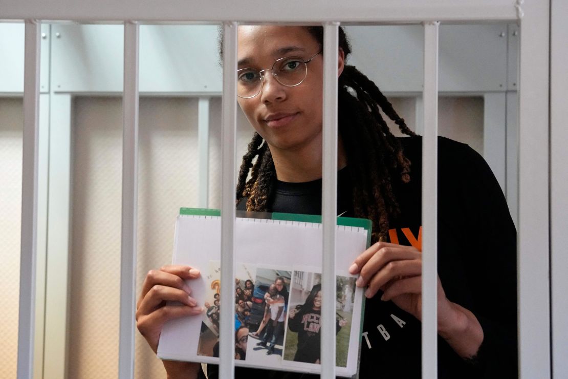 Brittney Griner holds photographs standing inside a defendants' cage before a hearing at a court outside Moscow Wednesday.