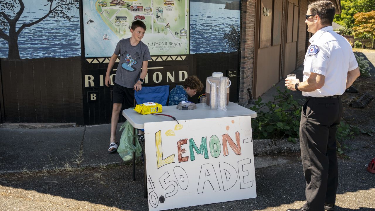 Gabe DeBay, a medical services officer with the Shoreline Fire Department, buys lemonade from Kaellan Robberts and Aven Josephy on Tuesday in Shoreline, Washington.