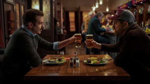 Ted Lasso (Jason Sudeikis) shares a toast with Coach Beard (Brendan Hunt) at the Crown & Anchor in an episode of 