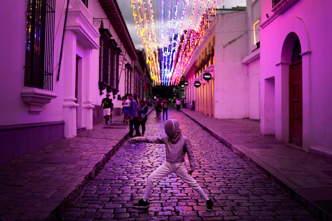 A young fencer strikes a pose for her parents as they take photos in Caracas, Venezuela, on Sunday, July 24.