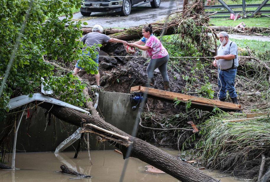 Tonya Smith reaches for food from her mother, Ollie Jean Johnson, to give to Smith's father, Paul Johnson, as they hang over a flooded Grapevine Creek in Perry County on Thursday. Smith's trailer was washed away; her father was staying the night in his home without power.