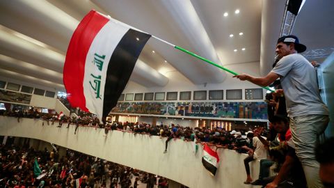 Supporters of cleric Muqtada al-Sadr wave flags in Iraq's parliament, inside Baghdad's high-security Green Zone, as they protest against a rival bloc's nomination for prime minister, on July 30, 2022.