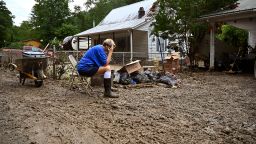Teresa Reynolds sits exhausted as members of her community clean the debris from their flood ravaged homes at Ogden Hollar in Hindman, Ky., Saturday, July 30, 2022. (AP Photo/Timothy D. Easley)