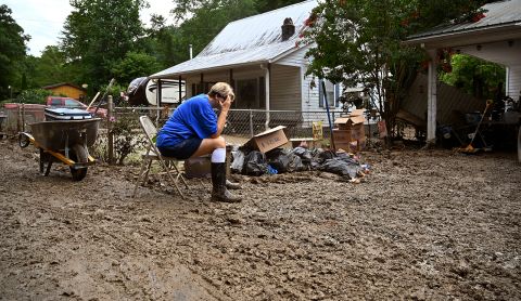 Teresa Reynolds sits exhausted as members of her community clean debris from flood-ravaged homes in Hindman, Kentucky, on Saturday, July 30.