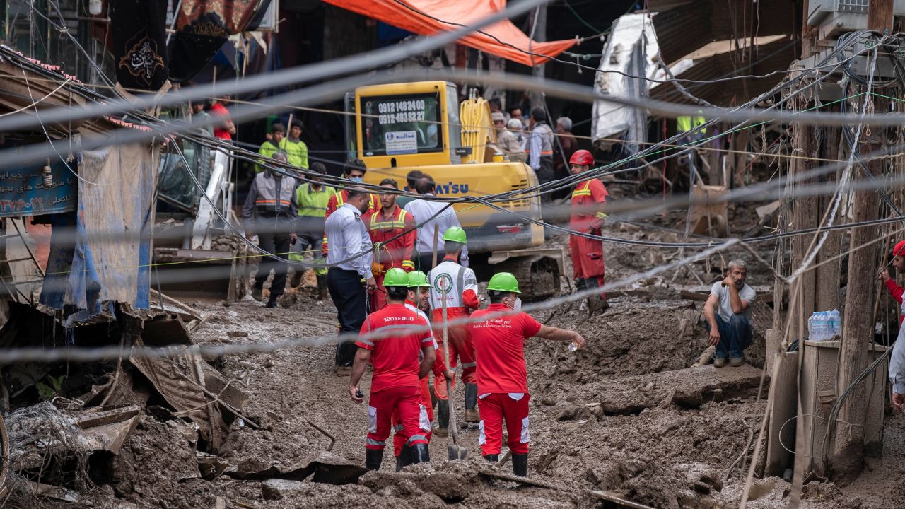 Rescue workers walk along an area damaged in flash flooding in northwestern part of Tehran on July 29, 2022.