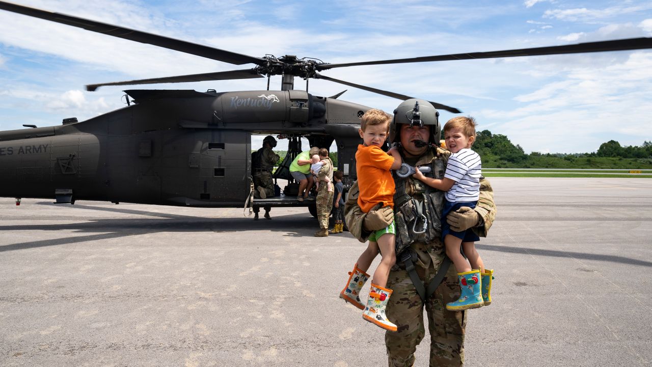Sgt. Thorin Brant of the Kentucky National Guard carries two children from a helicopter at the Wendell H. Ford Regional Airport after being airlifted from South Fork, Kentucky during a recon and rescue mission in Breathitt County, near Hazard, Kentucky.