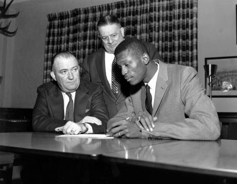 Russell, right, with Boston Celtics co-owners Walter Brown, left, and Lou Pieri, as Russell signs the contract to join the team in Boston, Massachusetts, in December 1956.