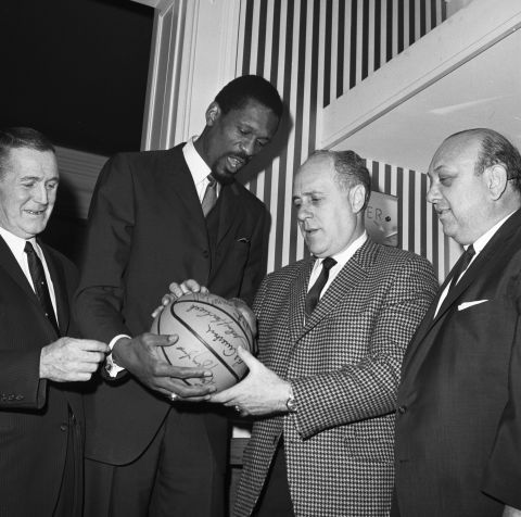 Russell, center left, and Auerbach look over an autographed ball after Russell was named Boston's head coach in 1966, making him the first Black head coach in NBA history.