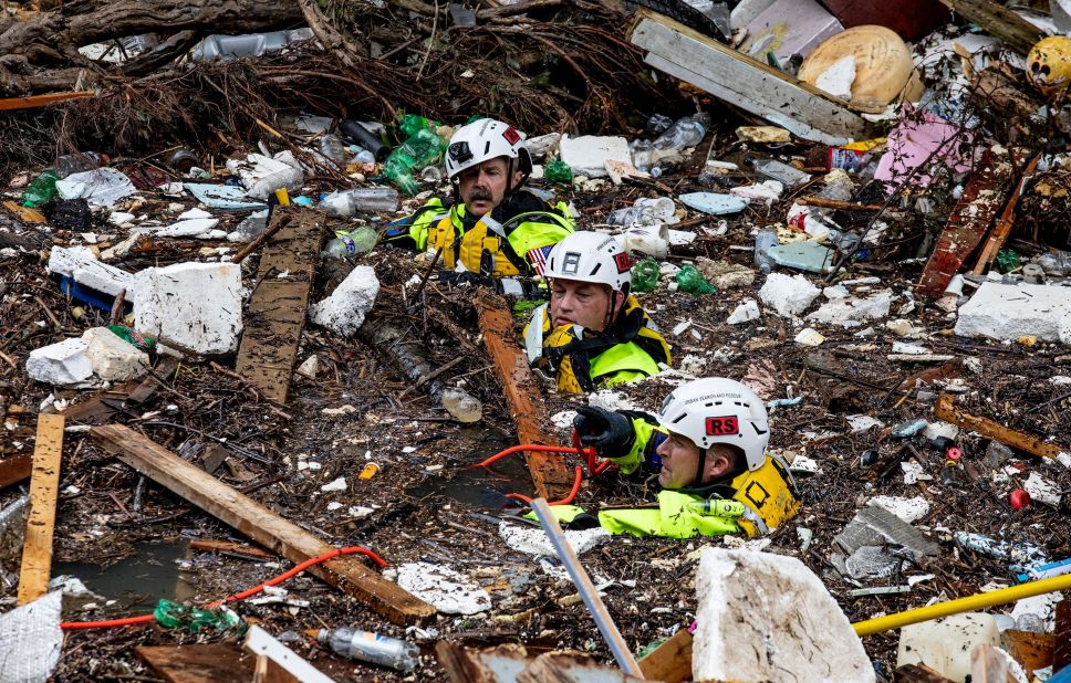 Members of a search-and-rescue team wade through the debris-filled Troublesome Creek after a search dog detected the scent of a potential victim in Perry County, Kentucky, on Sunday.
