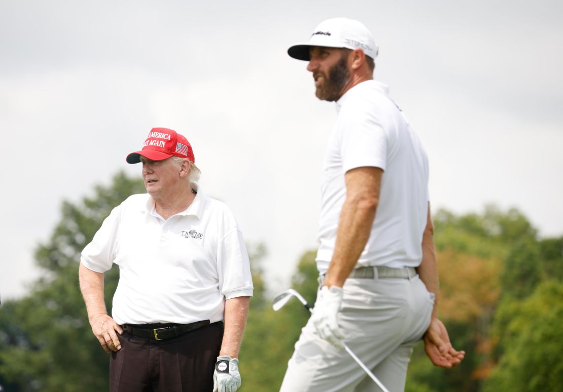 Trump looks on as Johnson plays a shot from the seventh tee during Thursday's pro-am.